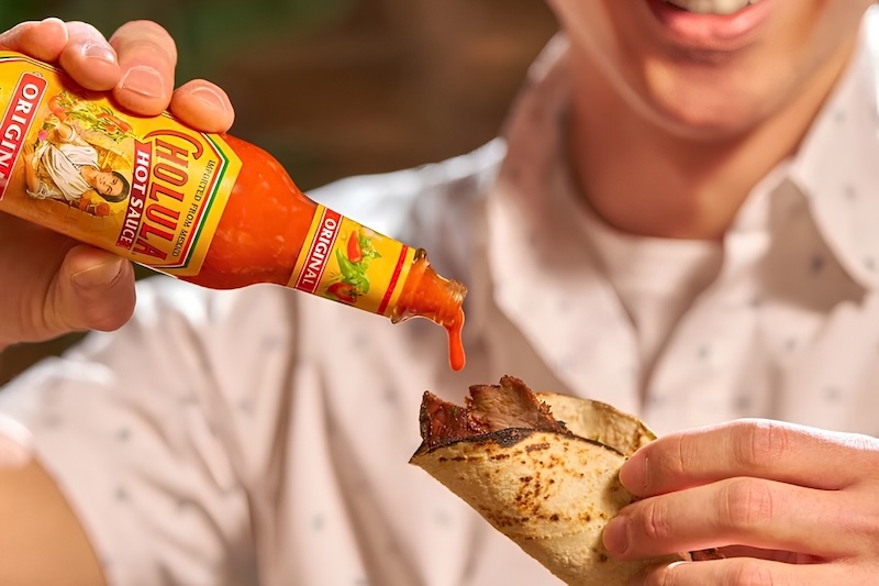Cholula hot sauce being poured on taco